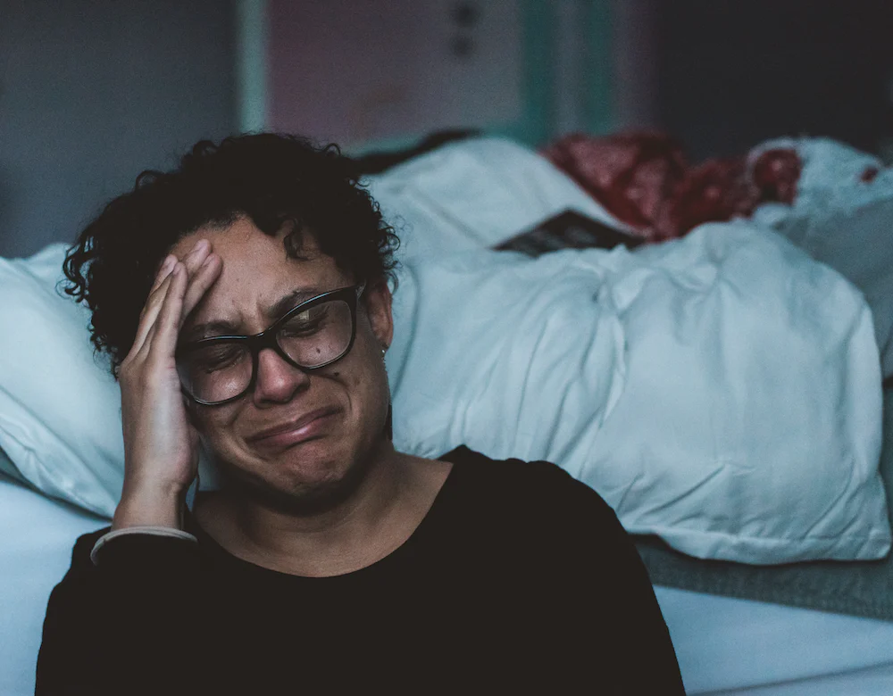 sleep deprived mom crying at edge of bed in the night