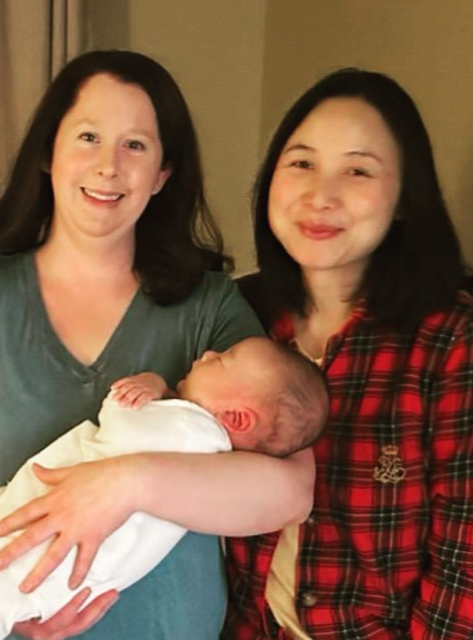 certified newborn care provider holding baby next to smiling mom.
