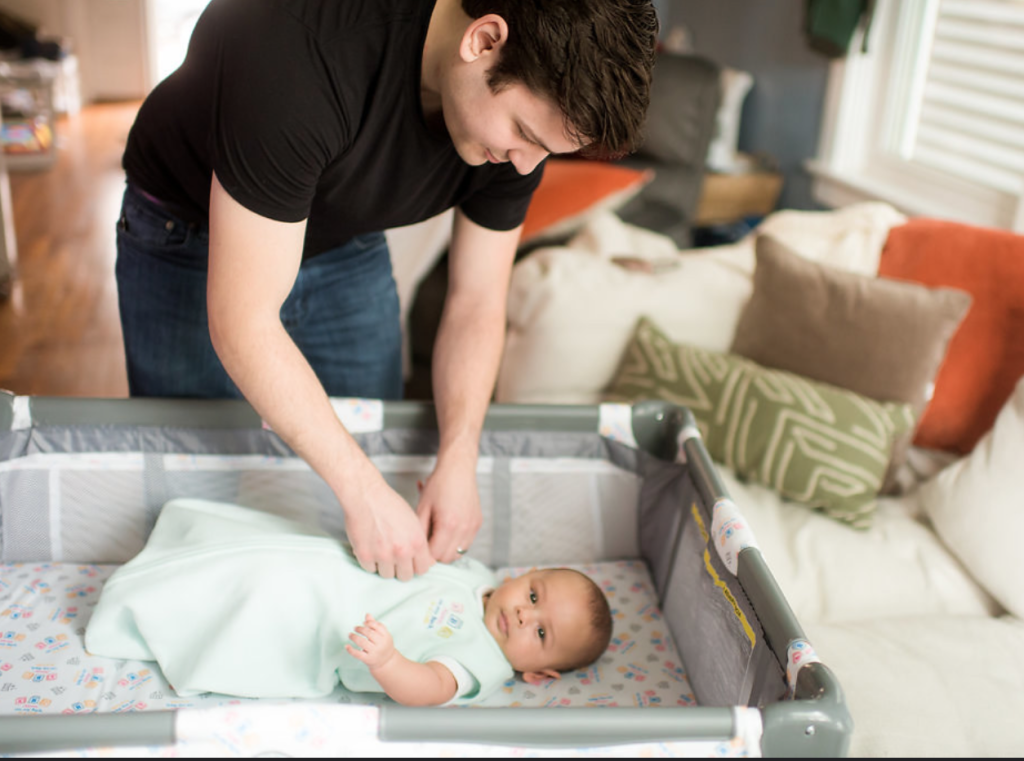 Dad putting newborn safely to sleep in crib. 