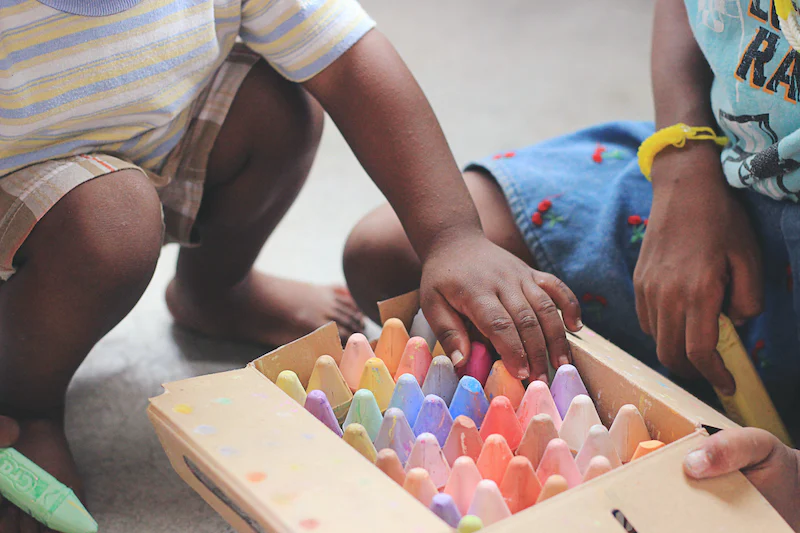 toddler choosing a large piece of chalk to draw with